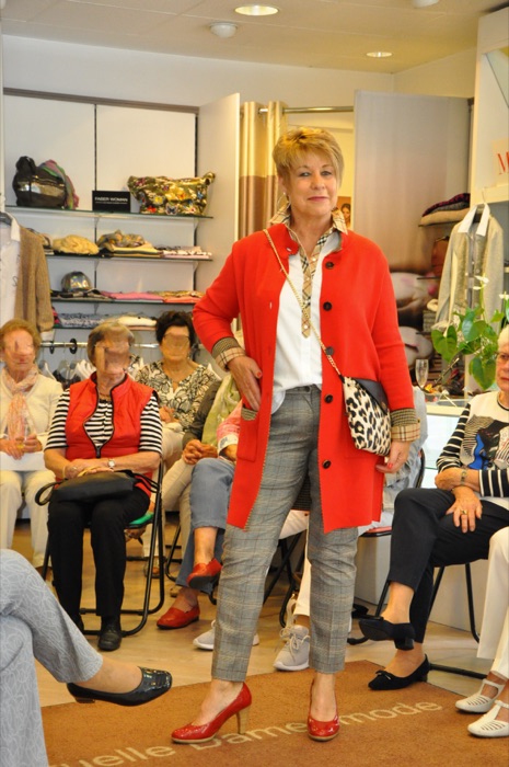 Modenschau: rote Jacke zu grauer Hose mit gemusterter Clutch