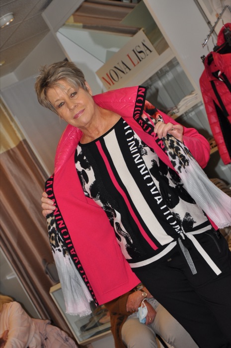 Pinkfarbene Jacke zu gemustertem Kleid mit Fransenschal