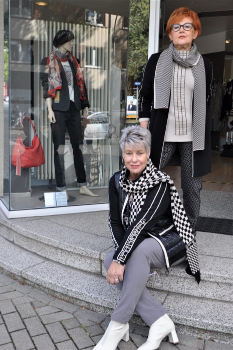 Zwei Kundinnen in Schwarz-Weiß-Outfits vor dem Schaufenster